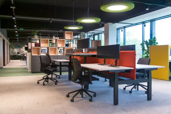 Sit-stand desks with ergonomic office chairs and red acoustic panel
